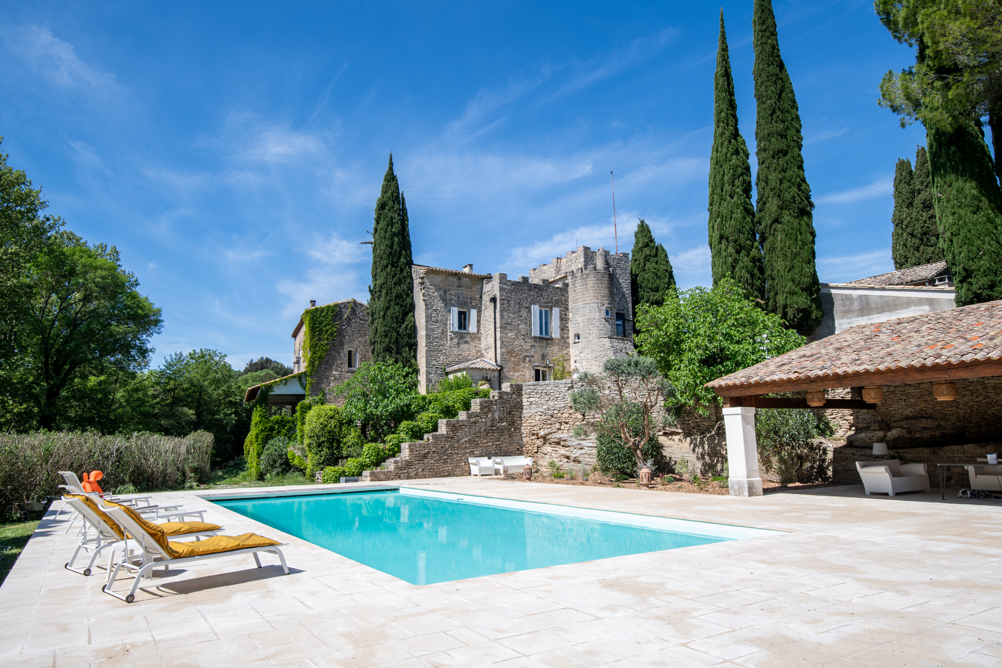 Fachada del Château Les Boissières rodeada de cipreses, propiedad de prestigio en el Gard
